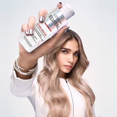 Frau hält Elvital Bond Repair Rescue Pre-Shampoo in der Hand