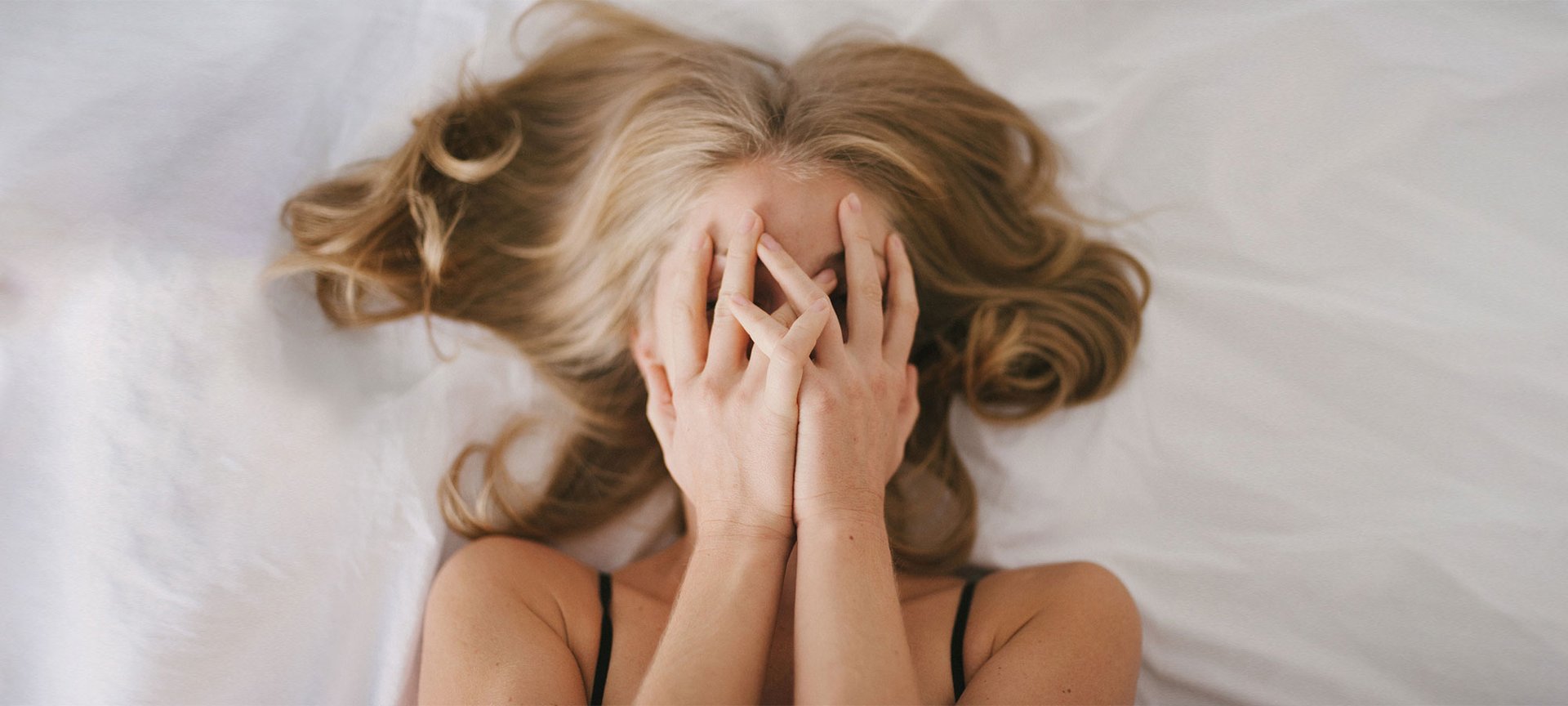 Frau mit aschblondem Haar liegt im Bett