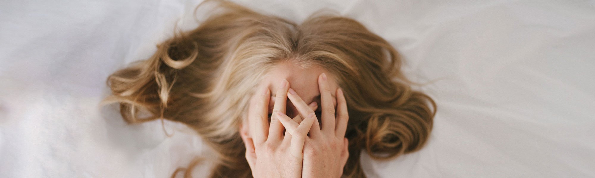 Frau mit aschblondem Haar liegt im Bett