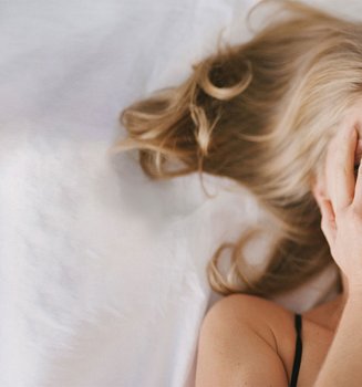 Frau mit aschblondem Haar liegt im Bett