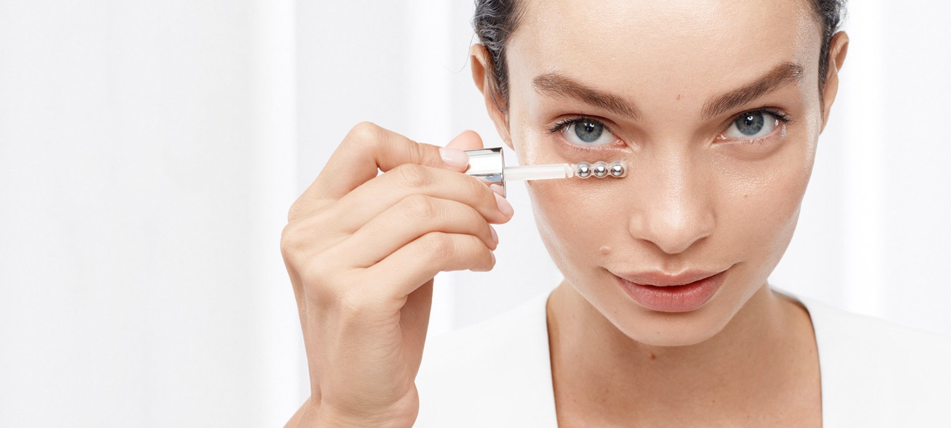 Ein junge Frau trägt ein Serum auf ihre Augenpartie auf