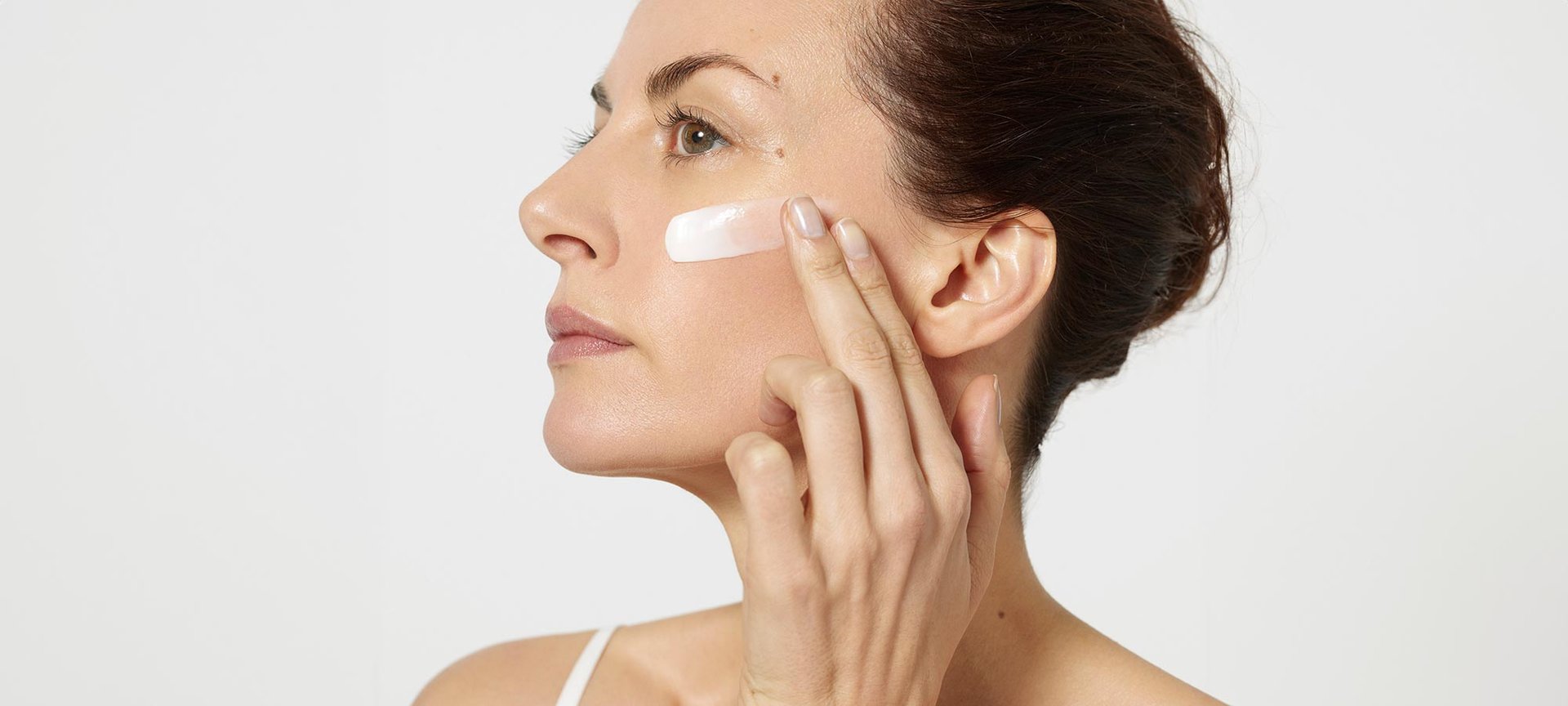 Eine Frau traegt Gesichtscreme auf