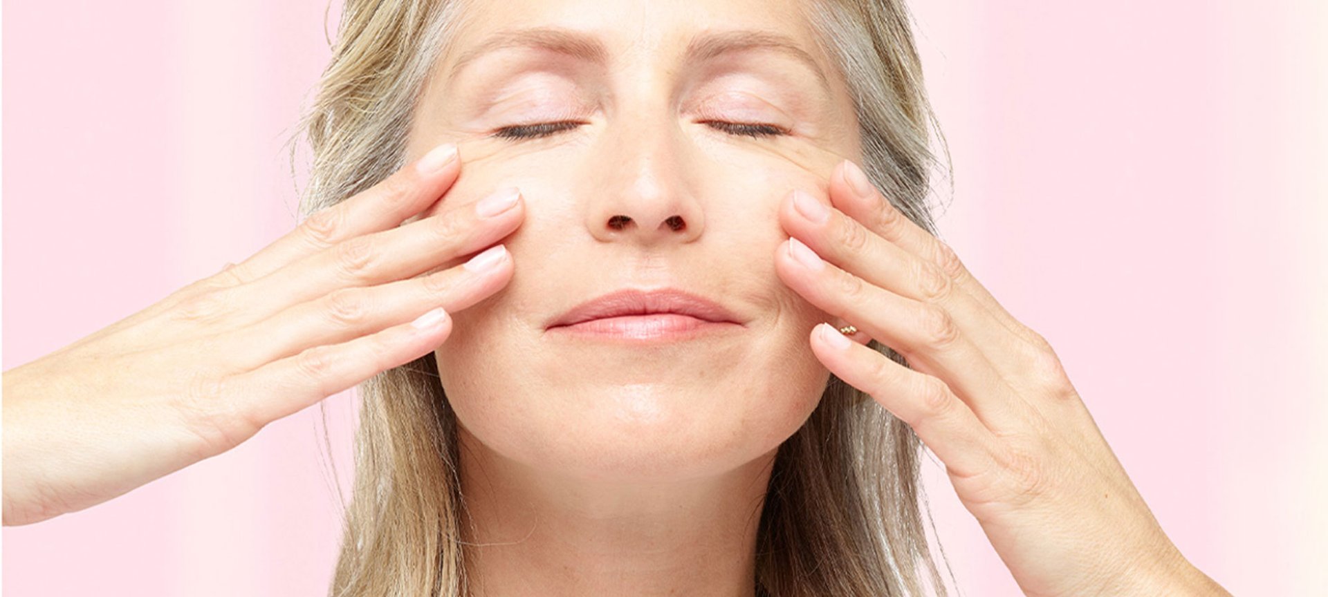 EIn Frau schließt ihre Augen und streicht sich mit ihren Händen über ihre Wangen
