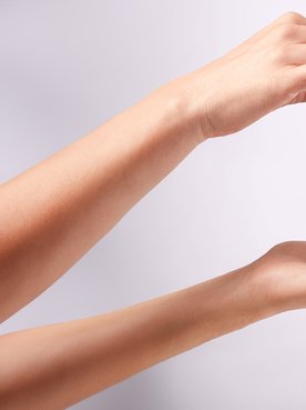 Eine rechte Hand einer Frau hält die Pipette von Revitalift Filler Anti-Falten Serum mit 1,5% purer Hyaluronsäure und tropft Serum auf die linke Handfläche