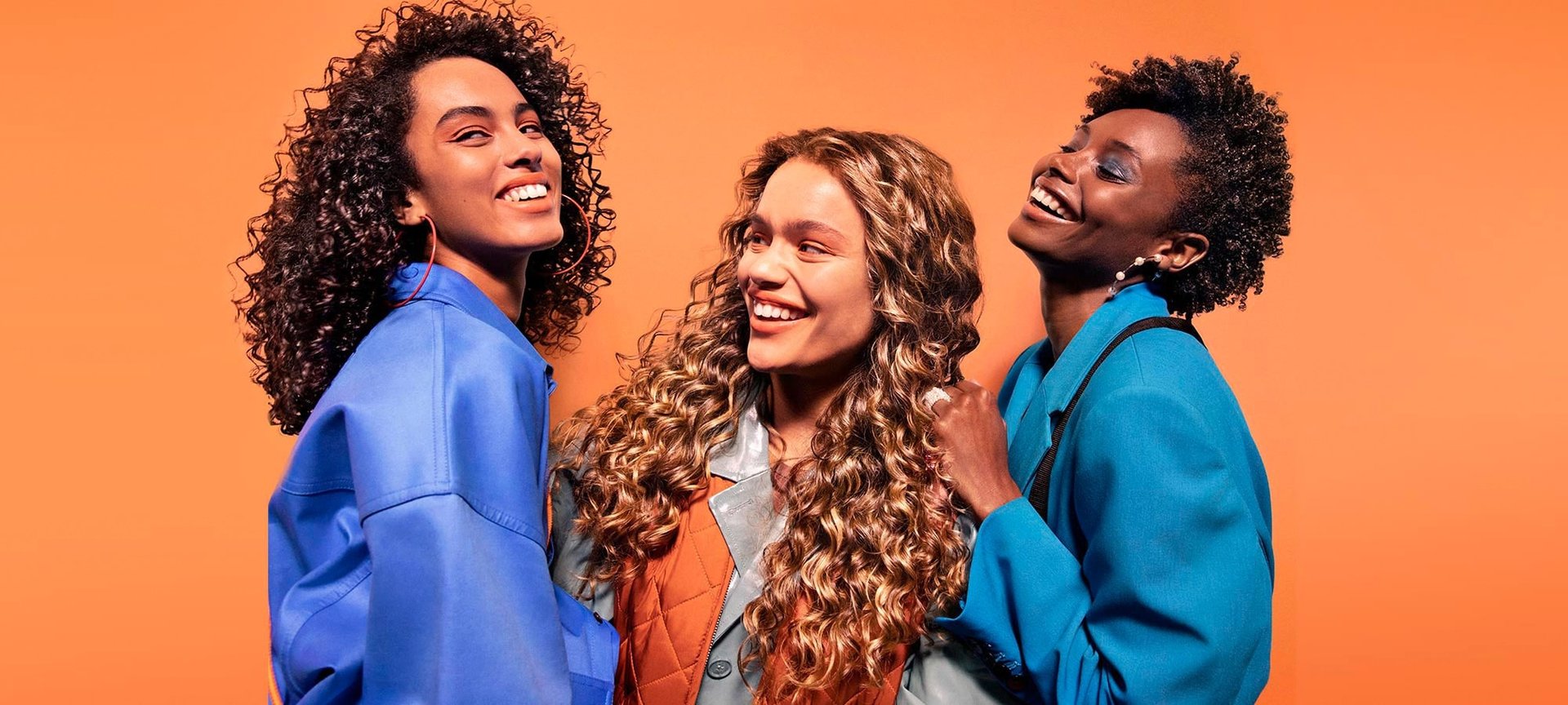 Drei junge Frauen mit schwarzen & blonden lockigen Haaren