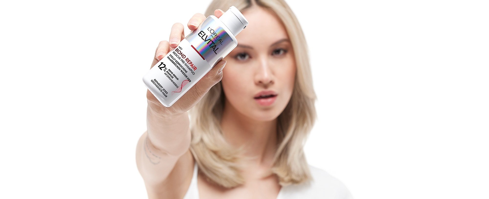 Eine Frau hält ein Elvital Bond repair in ihrer Hand