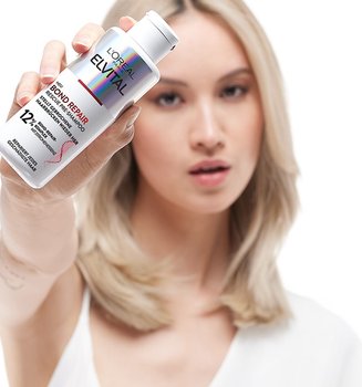 Eine Frau hält ein Elvital Bond repair in ihrer Hand