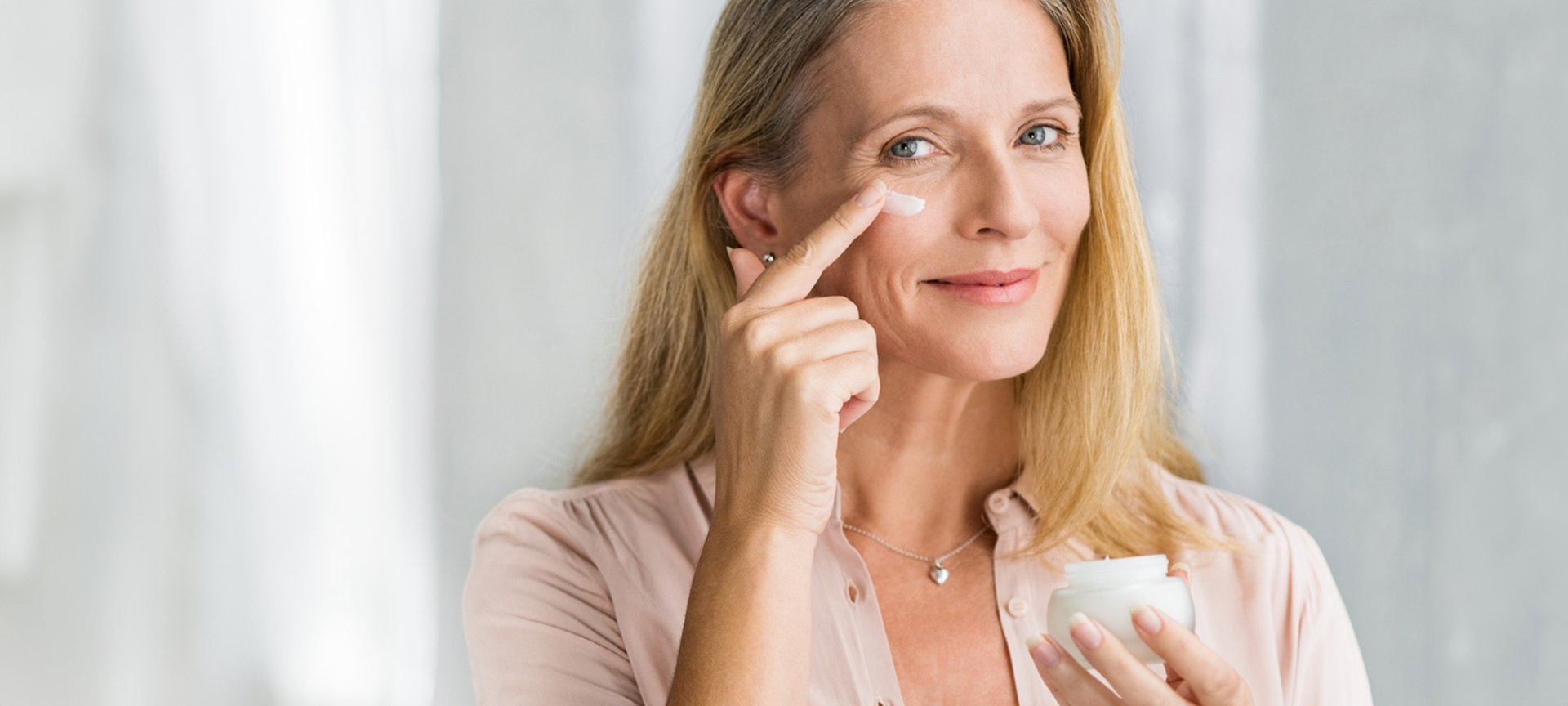 Eine Frau trägt auf ihre rechte Wange eine Creme auf