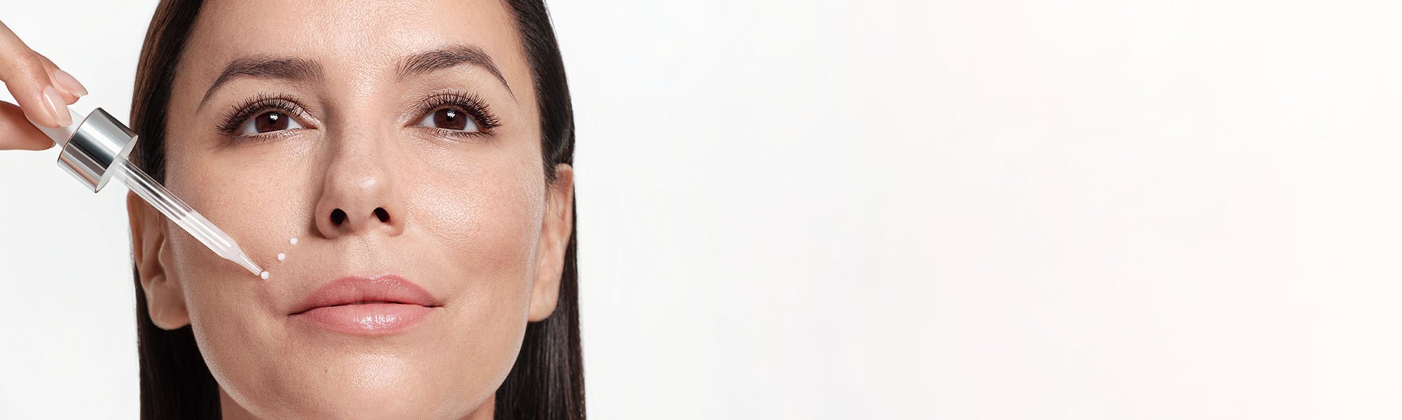 Eva Longoria trägt ein Serum mit Retinol mit einer Pipette auf ihre Wange auf