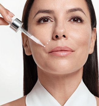 Eva Longoria trägt ein Serum mit Retinol mit einer Pipette auf ihre Wange auf