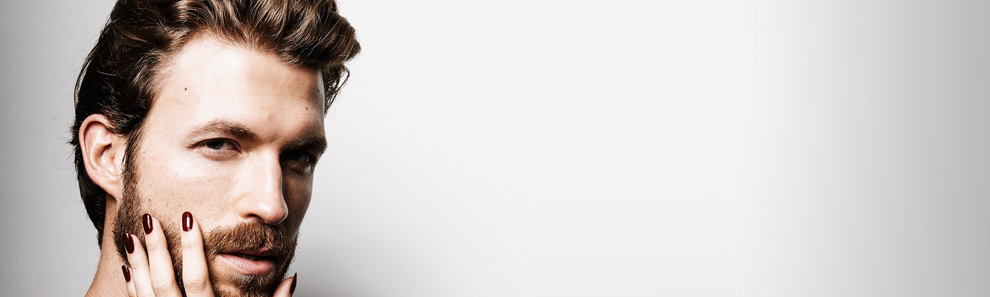 Mann mit getrimmten Bart wird von Frauenhand im Gesicht berührt