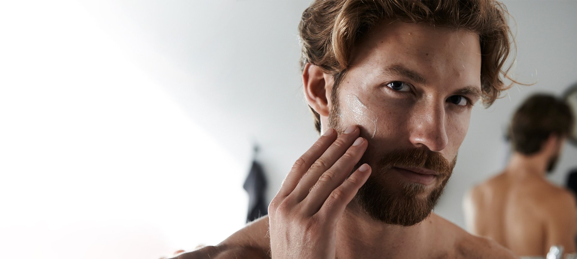 Ein Mann betrachtet sich und fühlt seinen Bart