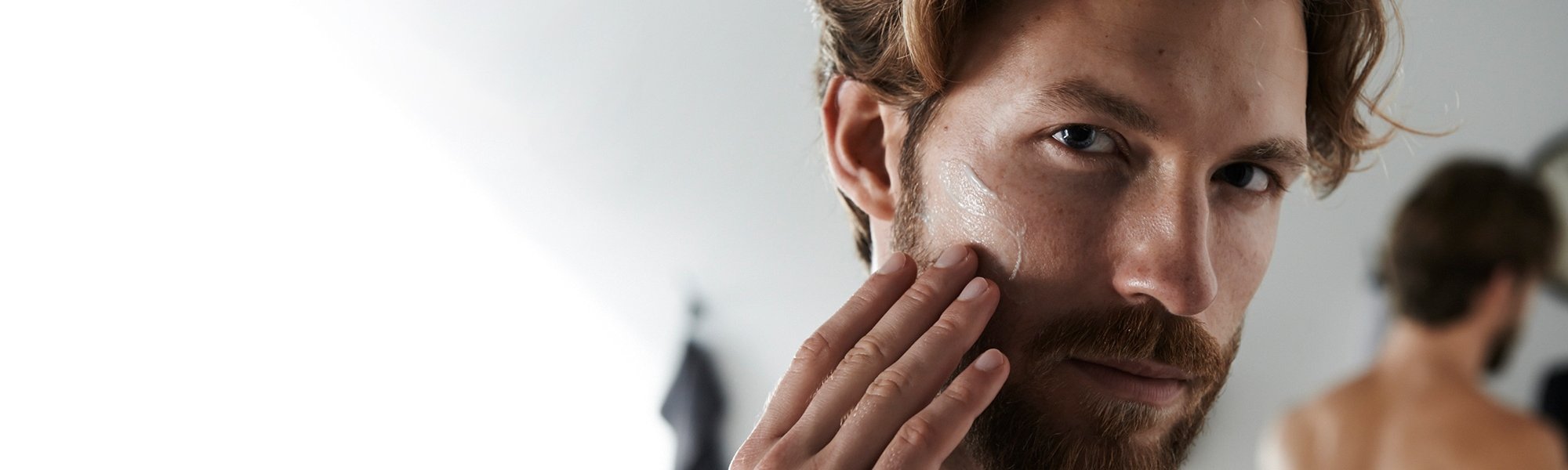 Ein Mann betrachtet sich und fühlt seinen Bart
