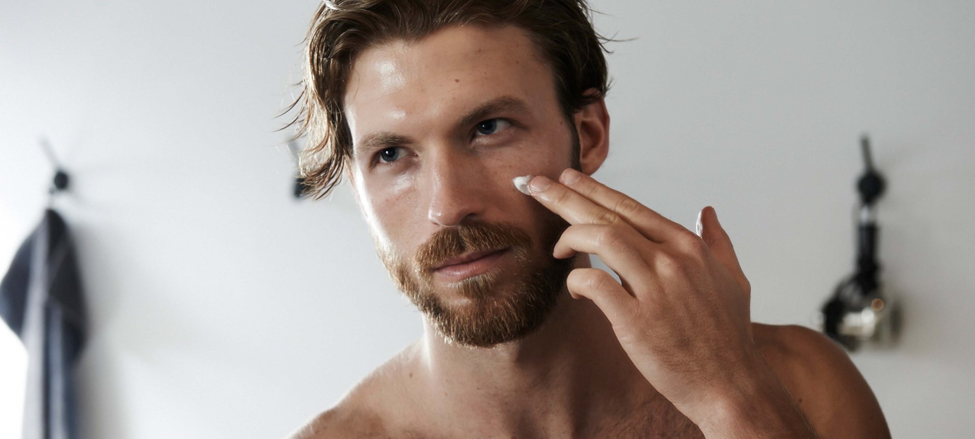 Mann mit Handtuch über der Schulter hat Hände auf der Gesichtshaut