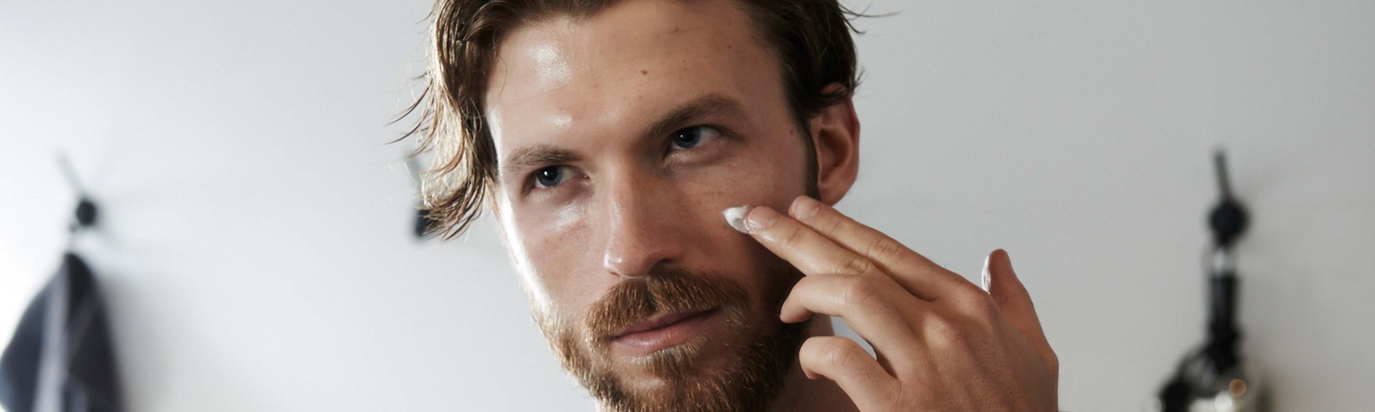 Mann mit Handtuch über der Schulter hat Hände auf der Gesichtshaut