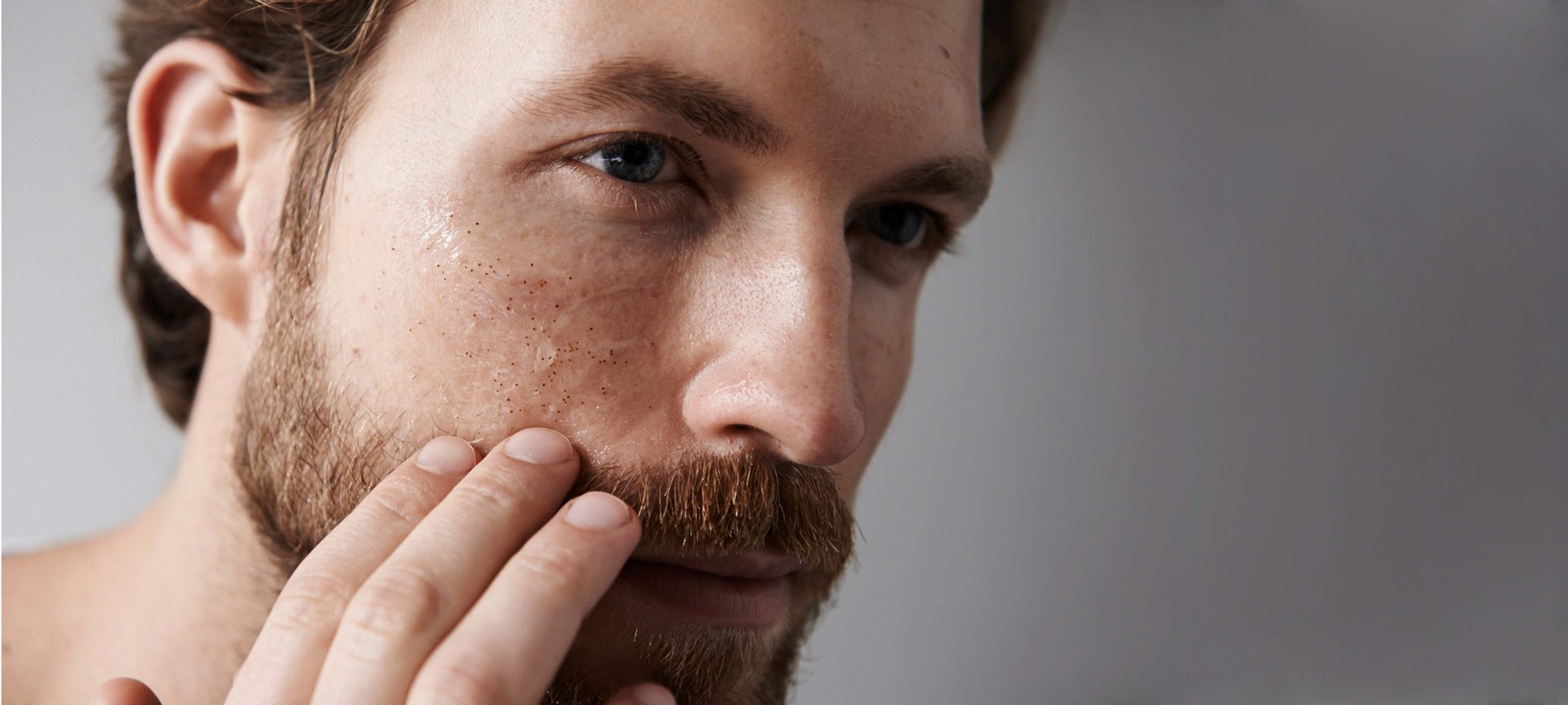 Ein Mann betrachtet sein Gesicht im SPiegel