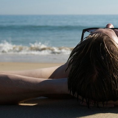 Junger Mann in Badehose liegt am Strand