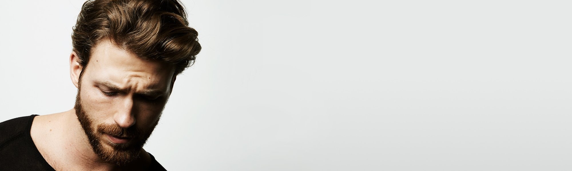 Mann mit gepflegten Haaren blickt nach unten