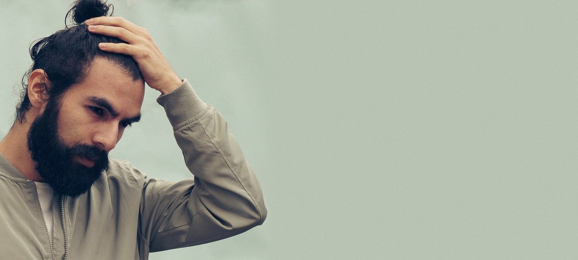 Mann mit langen Haaren streicht sich durch die Haare.