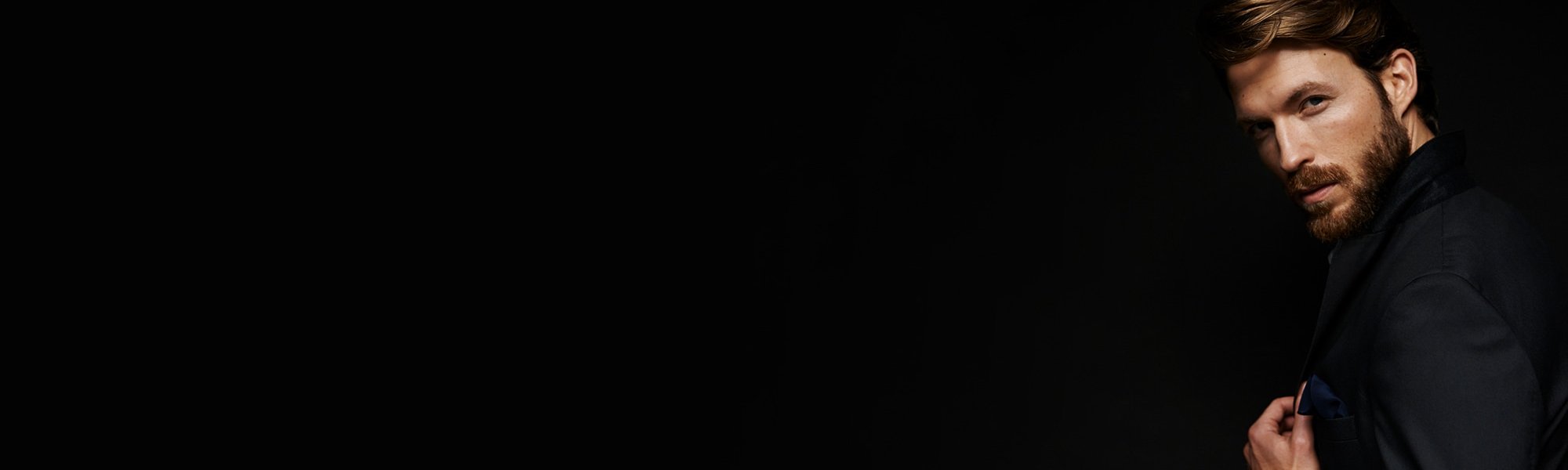 Junger Mann, blond, mit Vollbart schaut interessiert zur Seite