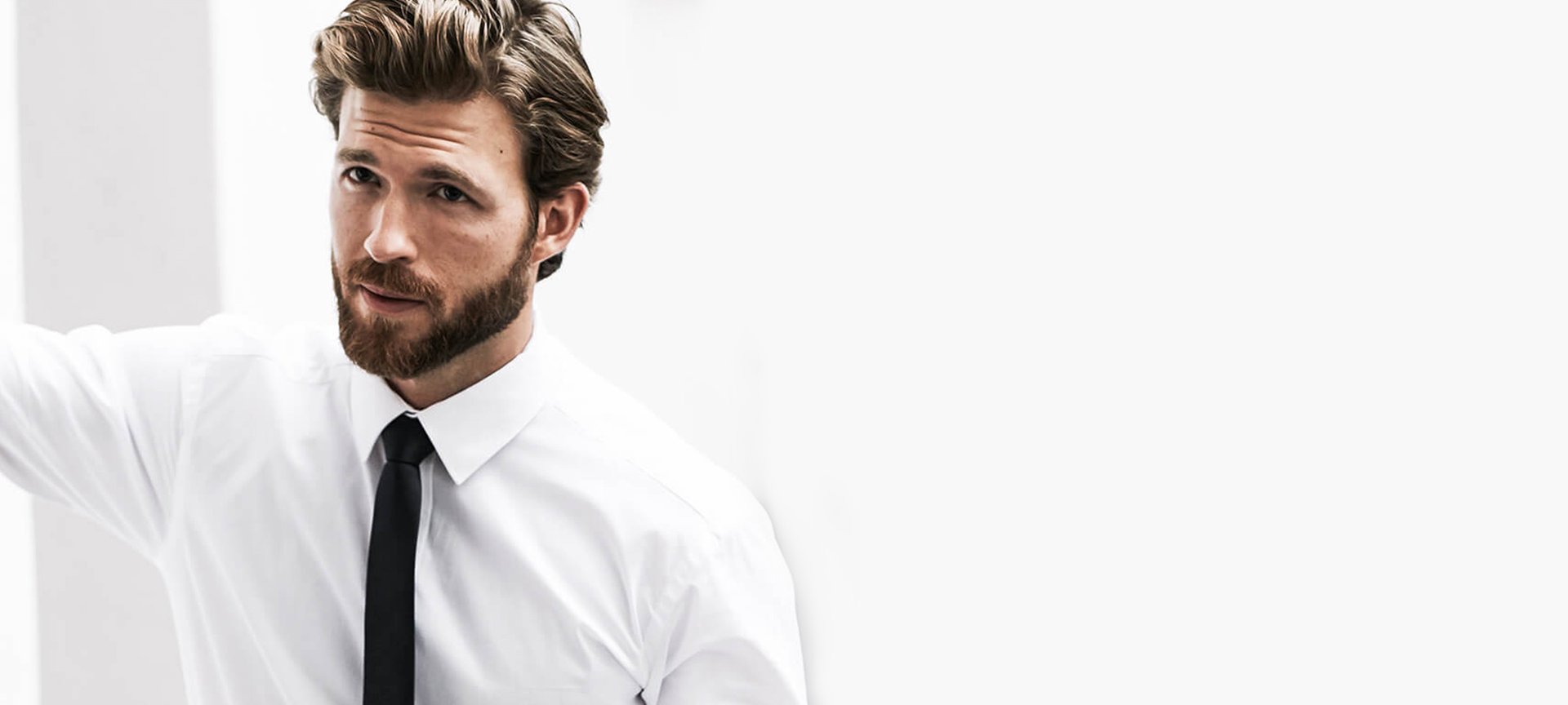 Mann mit Bart in weißem Hemd und schwarzer Krawatte