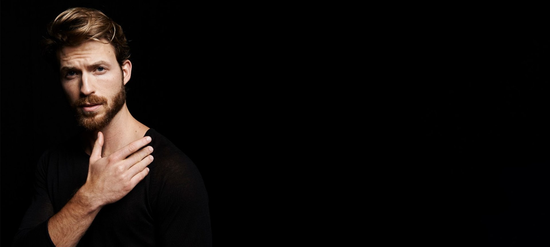 Ein Mann mit Vollbart vor dunklem Hintergrund