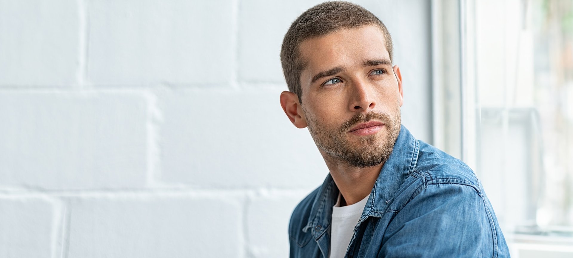 Ein junger Mann mit Kurzhaarfrisur schaut nachdenklich