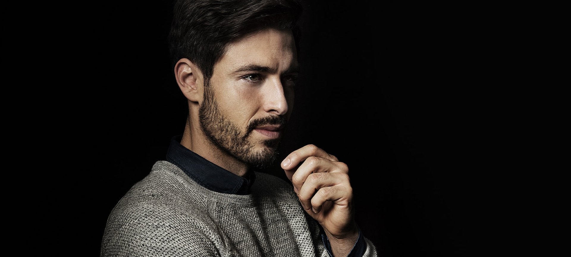 Mann mit Bart im seitlichen Profil und Hand am Kinn