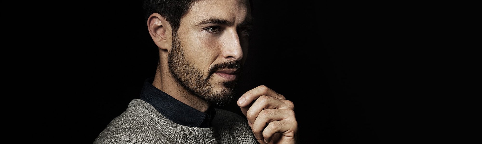 Mann mit Bart im seitlichen Profil und Hand am Kinn