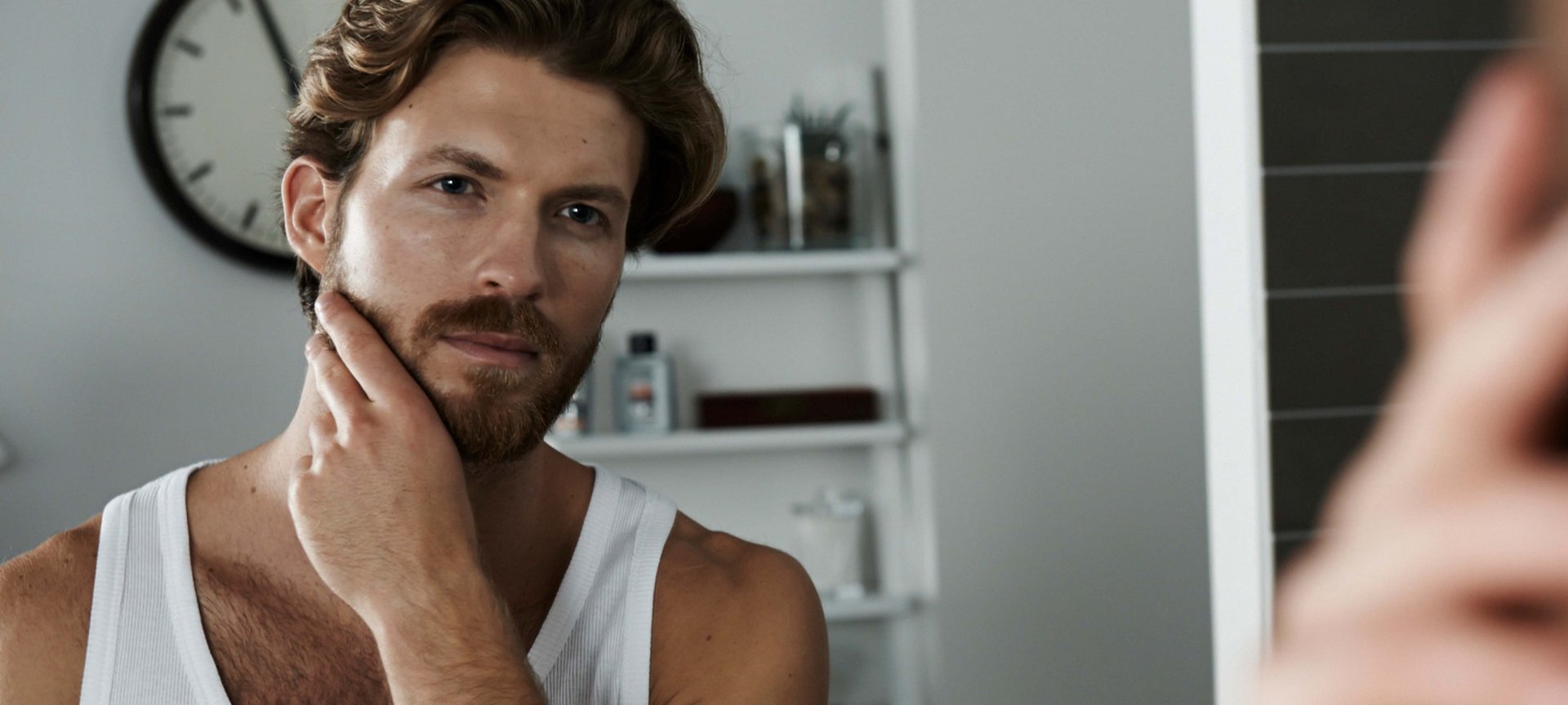 Ein Mann mit Bart betrachtet sich im Spiegel