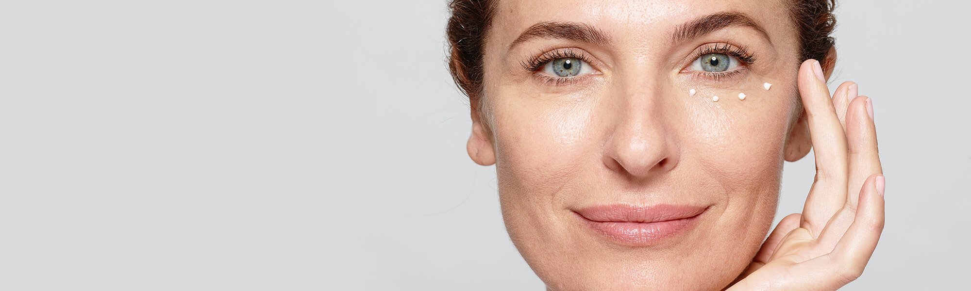 Eine Frau pflegt ihre Augen mit einer Creme