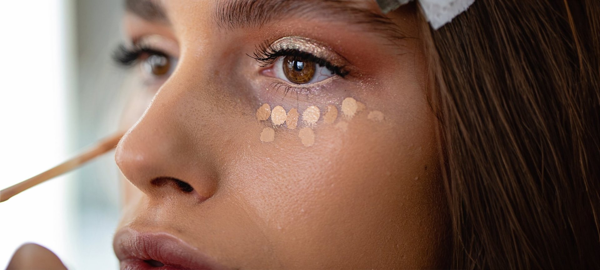 Frau tupft Concealer unter ihre Augen