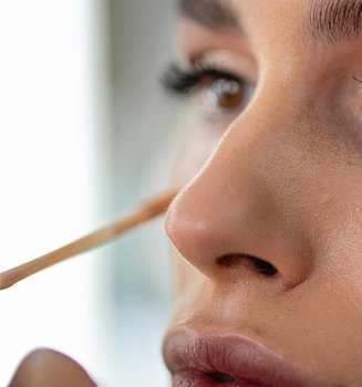 Frau tupft Concealer unter ihre Augen