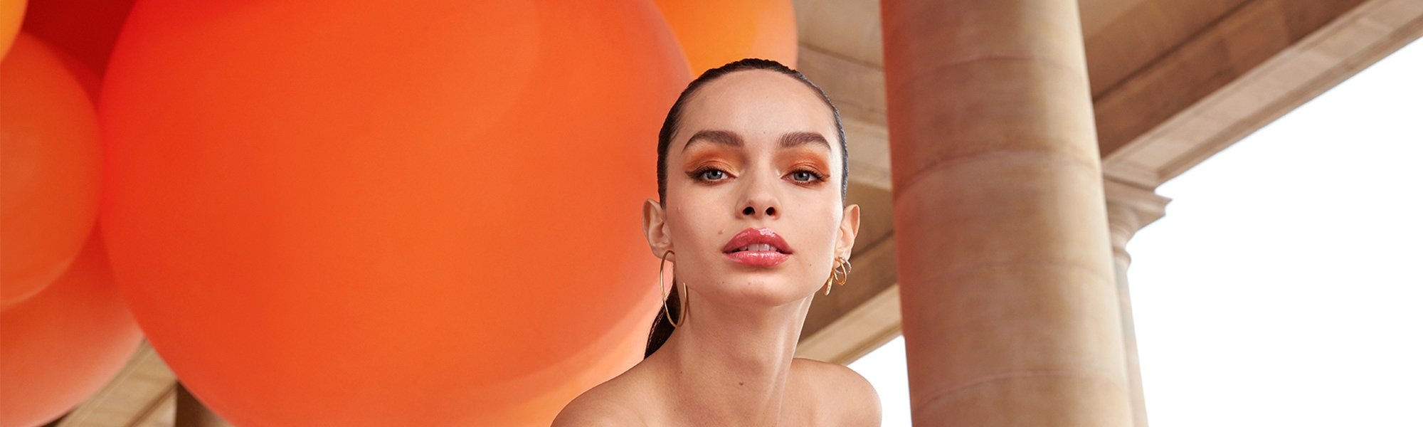 Eine Junge Frau mit zurückgebundenen Haaren und sommerlichem Make-up