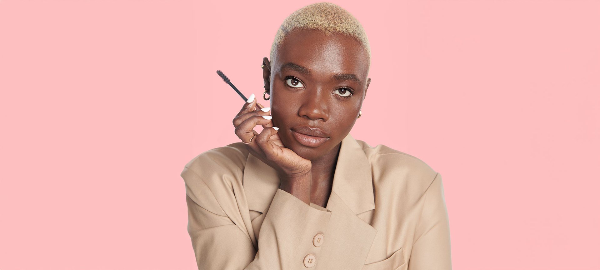 Eine junge Frau mit Kurzen Haaren und einer Mascara Bürste in ihrer Hand