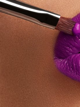 Volle Lippen werden mit Stift und Pinsel violett geschminkt