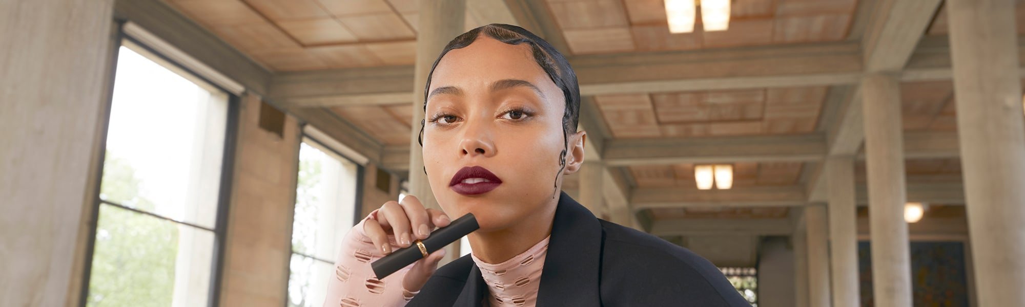 Ein Model trägt matten Lippenstift und hält die Hülse in der Hand