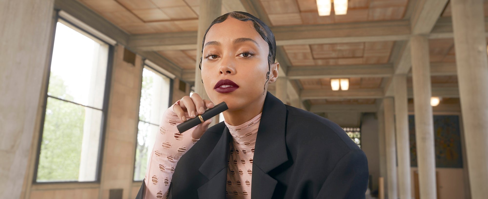 Ein Model trägt matten Lippenstift und hält die Hülse in der Hand
