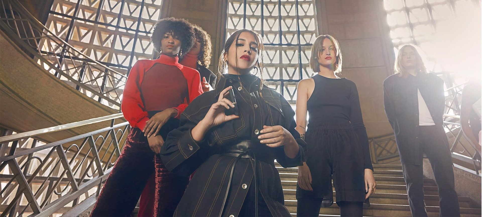 Fuenf Frauen posieren auf einer Treppe mit Lippenstift in einer Hand