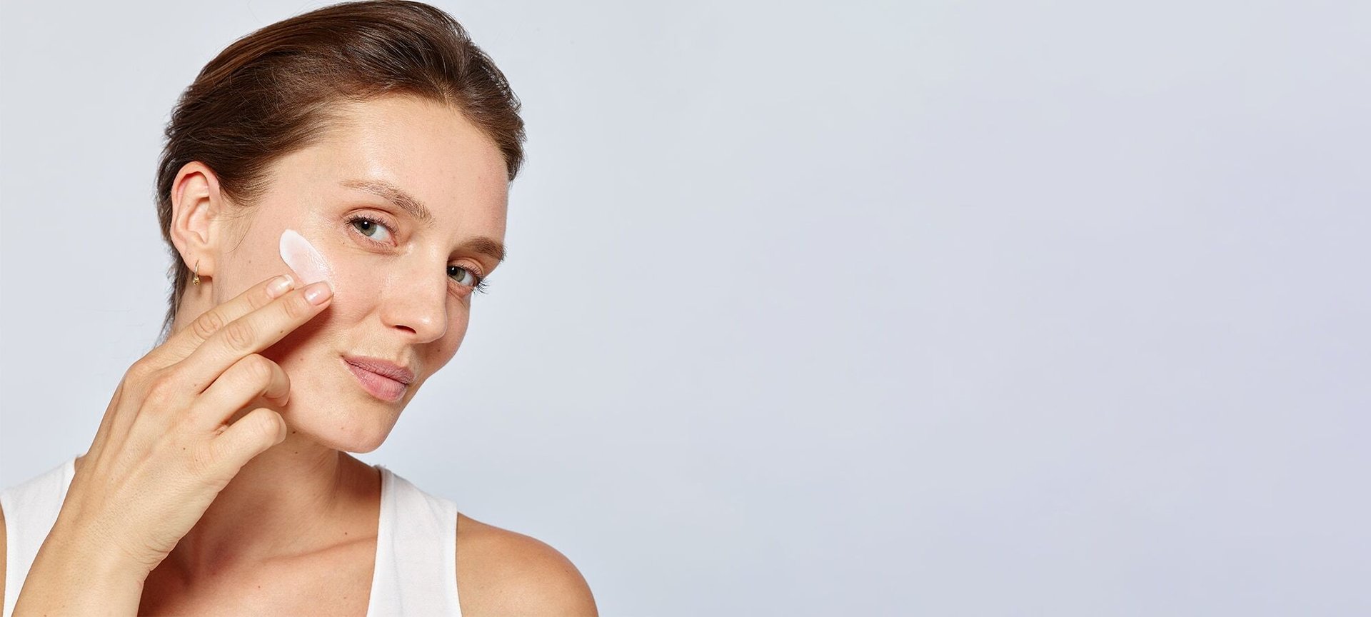 Frau trägt Creme auf die Wange auf