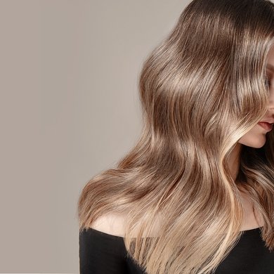 Junge Frau mit langen gewellten dunkelblonden Haaren schaut zur Seite