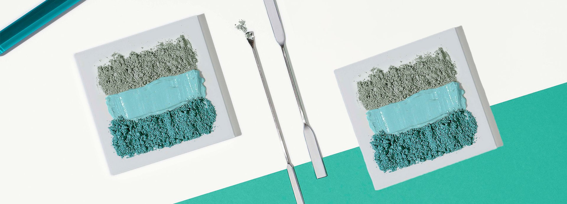 Verschiedenfarbige Tonerden ordentlich nebeneinander gereiht, daneben zwei Laborspachtel