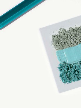 Verschiedenfarbige Tonerden ordentlich nebeneinander gereiht, daneben zwei Laborspachtel